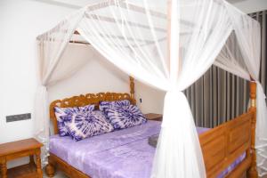 a bedroom with a bed with a canopy at Oshans Home - Guest House - Polhena in Matara