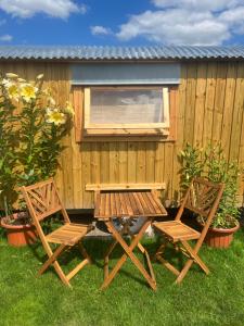 a picnic table and two chairs in front of a fence at Poachers Keep, Shepherds Hut in Endon
