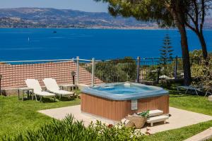a hot tub in a yard with a view of the water at Irilena Studios and Apartments in Lassi