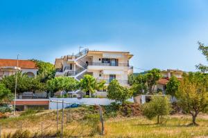 a building on a hill with trees in the foreground at Kottas Apartments in Paralia Vrachou