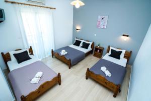 three beds in a room with blue walls at Kottas Apartments in Paralia Vrachou