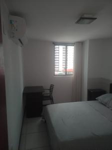 a bedroom with a bed and a desk and a window at Apto imperial Cabo branco in João Pessoa +26 photos