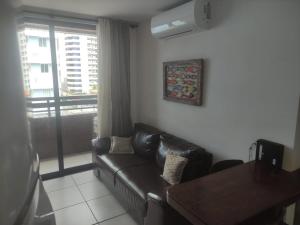 a living room with a leather couch and a window at Apto imperial Cabo branco in João Pessoa