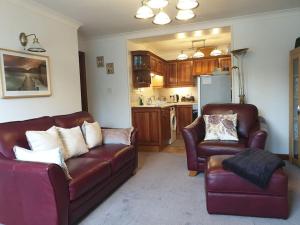 a living room with two leather couches and a kitchen at Lyndale self-catering apartment Sleeps 4 in Windermere