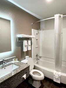 a bathroom with a toilet and a tub and a sink at Super 8 by Wyndham Cedar Rapids in Cedar Rapids