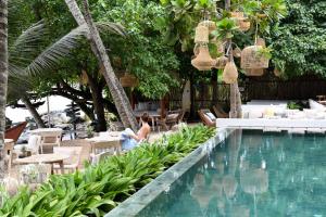 a woman sitting next to a swimming pool at Banana Bunks Mirissa in Mirissa