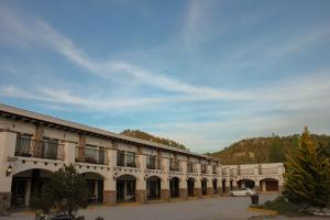 a building with a car parked in a parking lot at Hotel Quinta Mision in Creel