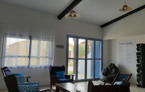 a living room with chairs and a table and windows at CasaMar: confortável e decorada, 30km do Chuí in Santa Vitória do Palmar