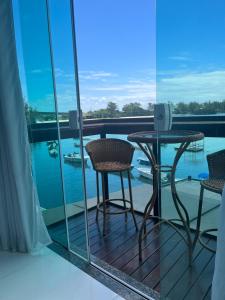 リオデジャネイロにあるPousada Seven Sunset Club Marambaiaの水辺の景色を望むバルコニー(テーブル、椅子付)