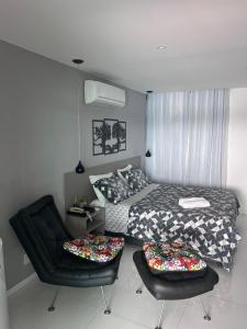 リオデジャネイロにあるPousada Seven Sunset Club Marambaiaのベッドと椅子のある寝室