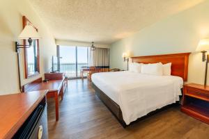 a hotel room with a bed and a balcony at The Oceanfront Inn - Virginia Beach in Virginia Beach