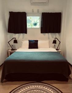 a bedroom with a bed with two lamps and a window at Holland Lodge Paramaribo in Paramaribo