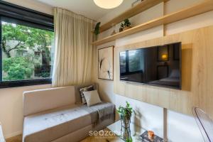 a living room with a couch and a tv and a window at Studio de luxo e Sofisticado no Moinhos LBO203 in Auxiliadora