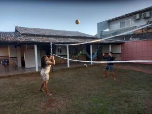 zwei Personen spielen mit einem Volleyballnetz vor einem Haus in der Unterkunft Casa com piscina in Palmas