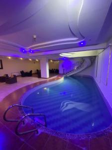 a large swimming pool in a room with purple lighting at Harvey's Guest House in Islamabad +30 photos