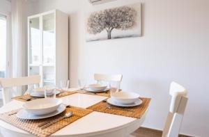 a white dining room with a table with plates and glasses at BENALBEACH Apartamento Exclusivo in Benalmádena