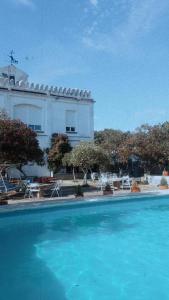 a large swimming pool with a building in the background at Hotel Rural El Vaqueril in Navas del Madroño