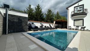 a swimming pool with chairs next to a house at Apartmani Nada in Pula