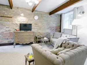 a living room with a couch and a tv at Barlow Country Club - Mill Farm Cottages in Dronfield