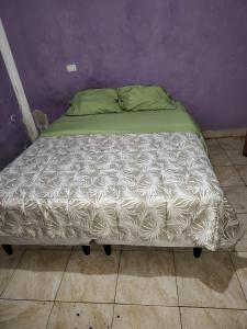 un lit défait dans une pièce avec un mur violet dans l'établissement Departamentos Catamarca, à San Fernando del Valle de Catamarca