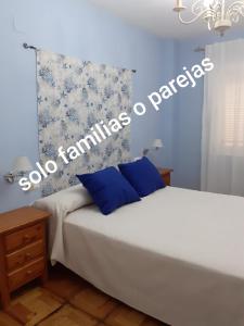 Un dormitorio con una cama blanca con paredes azules. en La casa familiar, en Puerto Real
