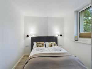 a white bedroom with a large bed with two pillows at Apartamenty Familly Dąbrówka - przy parku, prywatny parking, sauna, ogód - by SpaceApart in Jelenia Góra