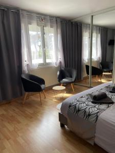 a bedroom with a bed and two chairs and windows at Chambres de l enclose in La Barre-de-Monts