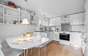 a white kitchen with a white table and appliances at Holiday Home Bjørnsknudevej Juelsminde Iii in Juelsminde +9 photos