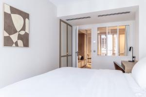 a bedroom with a white bed and a window at Quartier Libre Opera in Paris