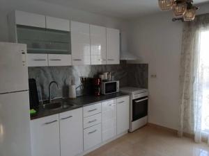 a kitchen with white cabinets and a sink and a microwave at Yellow House in Eleftheroúpolis