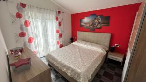 a bedroom with a red wall with a bed and a table at Apartmani Nada in Pula +36 photos