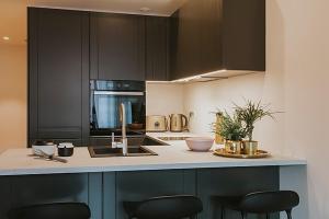 a kitchen with black cabinets and a counter with chairs at Cozy studio next to old town in Rotermann Quater in Tallinn