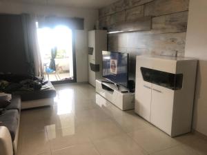 a living room with a white refrigerator and a tv at Magic Paradisus guest in Caniço