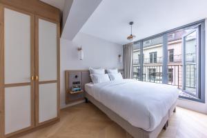 a bedroom with a large white bed and a large window at Quartier Libre Opera in Paris