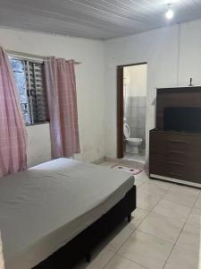 a bedroom with a bed and a flat screen tv at Kitnet para Temporada na Praia Simples in Bertioga