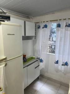 a small kitchen with a refrigerator and a window at Kitnet para Temporada na Praia Simples in Bertioga