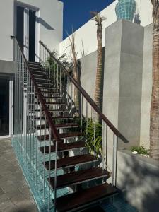 a metal staircase with glass railings and palm trees at Emerald Suite Summerstrand in Gqeberha