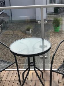 a glass table on a balcony with two chairs at Kosmos nad morzem in Dziwnówek