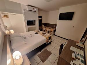 a small bedroom with a bed and a television at Mamaloo Pousada in Maceió