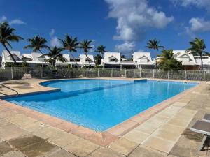 a large swimming pool with palm trees in the background at Paradise Beach Impressive 2 bedrooms seafront in Baie Nettle