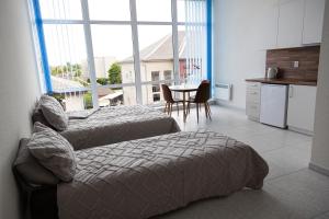 a bedroom with two beds and a kitchen with a window at ROOMS Park in Skuodas