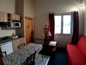 a small kitchen with a table and a red couch at Gîte de séjour et d'étape l'Escampette in Saint-Jean-du-Bruel