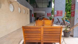 a restaurant with wooden chairs and tables in a building at Beach Class Convention - Flats em Boa Viagem por Yolo in Recife