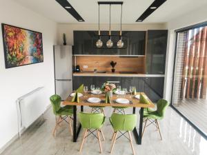 a dining room with a wooden table and green chairs at NOVA House Apartments in Delniţa