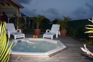 een hot tub op een houten terras met witte stoelen bij Gites de Bois d'Inde in Saint-François