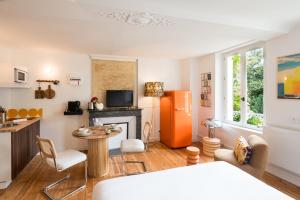 a kitchen and living room with a refrigerator and a table at Villa Robs - Studios et Appartements - Localisation idéale in Caen