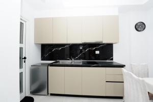 a kitchen with white cabinets and a sink at Vila 42 in Vlorë