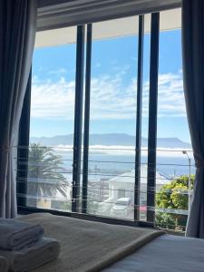 a bedroom with a large window with a view of the ocean at Little Penguin in Simonʼs Town
