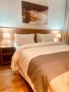 ein Schlafzimmer mit einem großen Bett und einem Nachttisch mit zwei Lampen in der Unterkunft Apart Hotel Luxo em Canela 201 in Canela