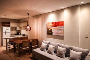 ein Wohnzimmer mit Couch und Tisch und eine Küche in der Unterkunft Apart Hotel Luxo em Canela 201 in Canela